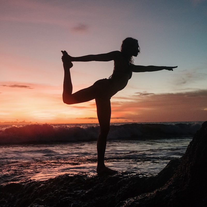 silhouette of woman standing on rock during sunset