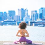 woman doing yoga facing calm body of water