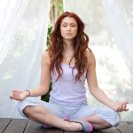 woman doing yoga pose sitting on wooden ground