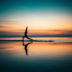 silhouette of person standing on seashore during sunset