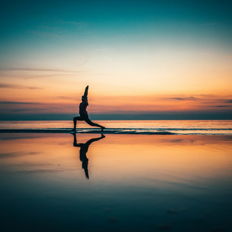 silhouette of person standing on seashore during sunset
